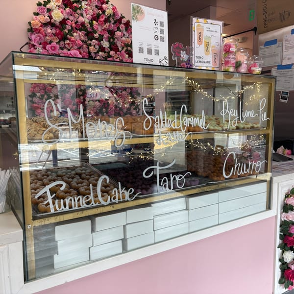 A glass display case filled with various pastries like funnel cake, churros, and key lime pie.